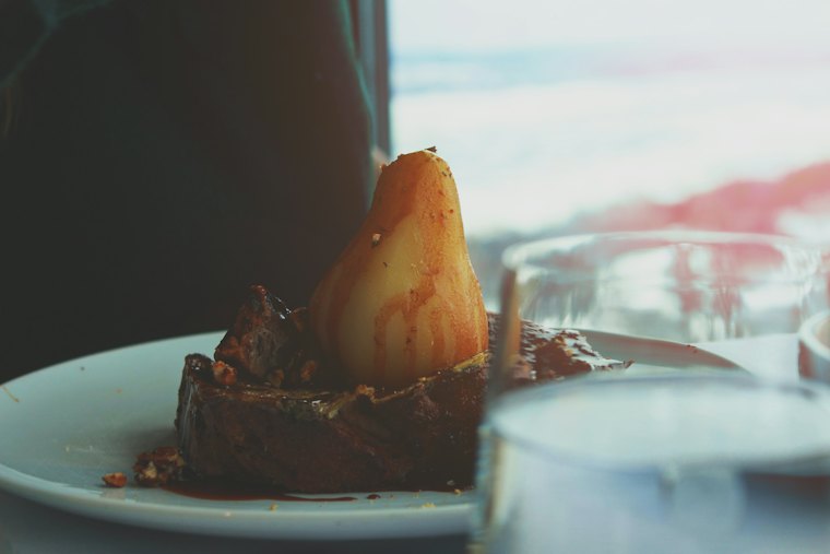 Dessert : poire pochée sur une assiette blanche.